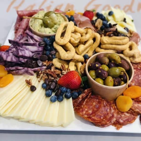 A large charcuterie board with meats, cheeses, olives, blueberries, nuts, and taralli.