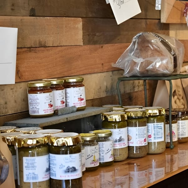 Jars of Altamura Pizza's sauces and spreads, with a loaf of bread, on wooden shelves.