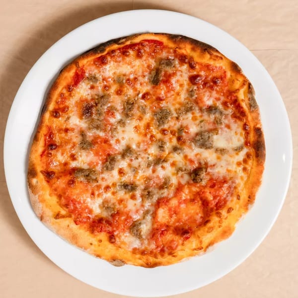 A whole sausage pizza with melted cheese and tomato sauce on a white plate.