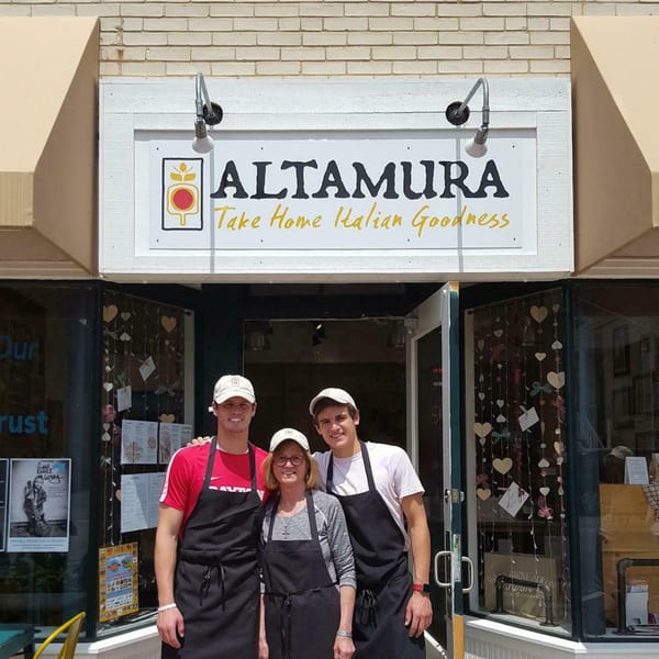Three smiling Altamura employees, two men and one woman, stand in front of the Italian restaurant.