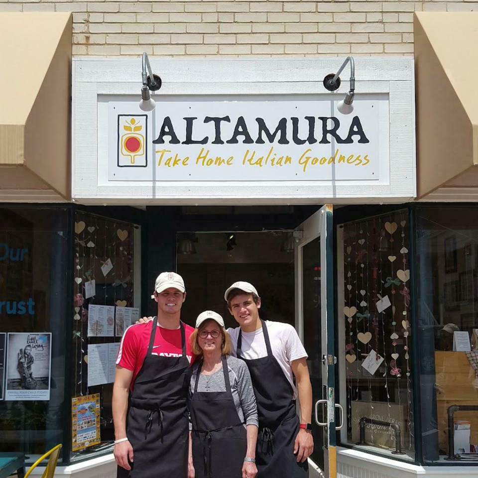 Three smiling Altamura employees, two men and one woman, stand in front of the Italian restaurant.