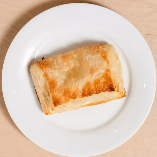 Golden-brown pastry puff on a white plate, viewed from directly above.