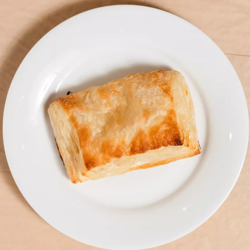 Golden-brown pastry puff on a white plate, viewed from directly above.