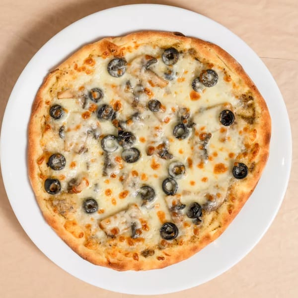 Round pizza with melted cheese, black olives, and mushrooms on a white plate.