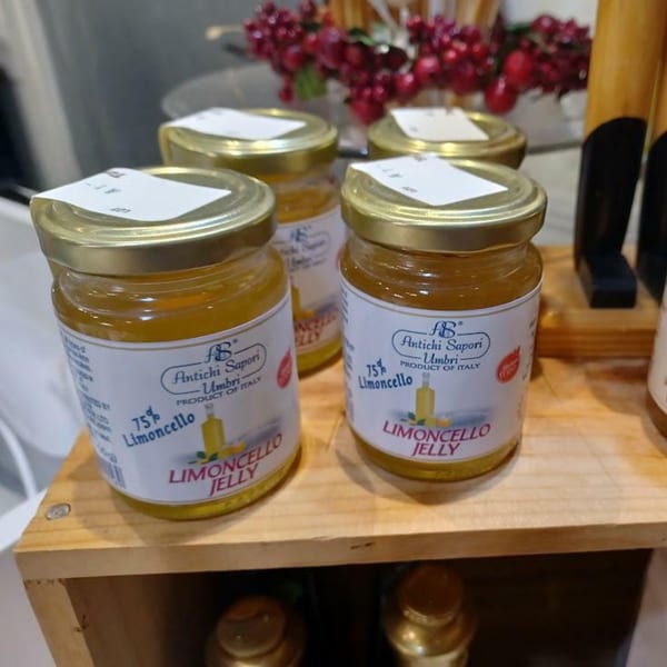 Four jars of Limoncello Jelly from Antichi Sapori Umbri, Italy, on a wooden shelf.