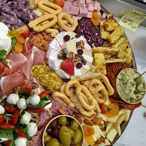 A large charcuterie board with various cheeses, meats, olives, nuts, and crackers.